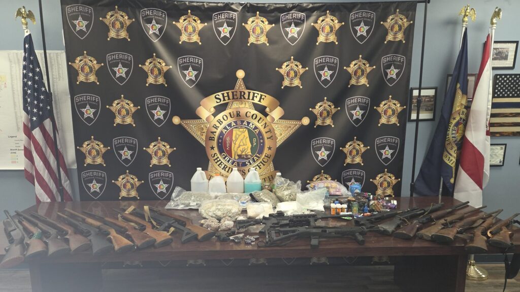 Narcotics, cash and firearms recovered by the Barbour County Sheriff's Office displayed in front of the Sheriff's Office backdrop